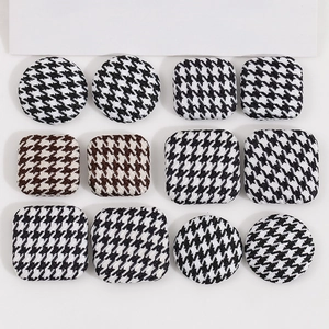 Flat lay of houndstooth fabric buttons in square and round shapes for DIY sewing projects