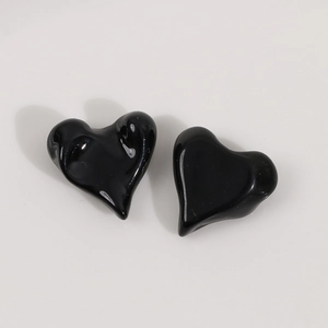 Close-up of glossy black heart resin charms with a smooth reflective mirror surface