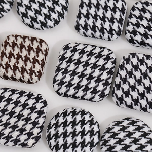 Detailed macro view of black and white houndstooth fabric buttons in square and round shapes