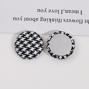 Detailed macro view of black and white houndstooth fabric buttons with metal backings