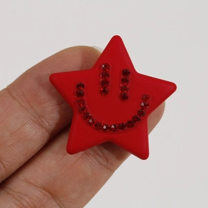 Close-up of red acrylic star charm with a sparkling rhinestone smiley face detail