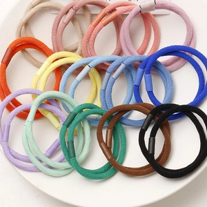 Detailed macro shot of various colorful high-elasticity hair ties on a ceramic plate