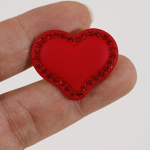 Macro view of red heart-shaped acrylic accessory with sparkling rhinestone edges