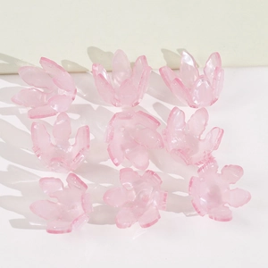 Détail macro de neuf perles fleurs en résine translucide rose clair pour la bijouterie