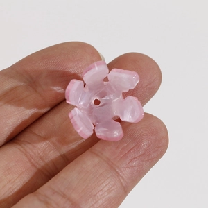 Gros plan d'une petite fleur en résine rose clair à six pétales avec trou pour le DIY