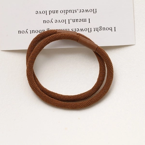 Detailed macro view of two brown high-elasticity hair ties with fine ribbed texture