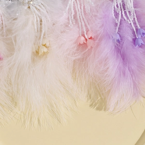 Détail de plumes d'autruche avec pompons en perles et petits pendentifs tulipes