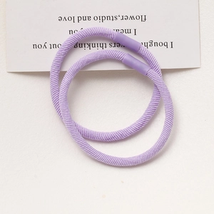 Detailed view of two purple high-elasticity hair ties with spiral braided texture