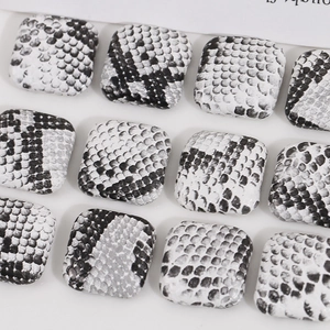 Macro detail of square black and white snake skin pattern resin charms for DIY jewelry