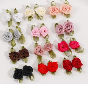 Close-up of small handmade satin ribbon roses with green leaves in various colors