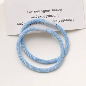 Detail view of two light blue elastic hair ties with textured fabric and matte plastic buckle