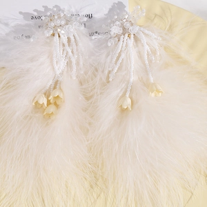 Vue détaillée de boucles d'oreilles en plumes d'autruche faites main avec perles de verre