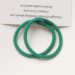Detail of two forest green high-elastic hair ties with spiral texture and smooth connectors