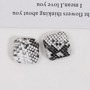 Square faux snake print earrings with black and white scale texture on a modern card