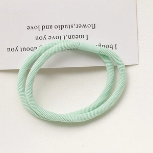 Detail of two mint green high-elastic hair ties with ribbed fabric and plastic buckles