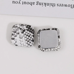 Close-up of square DIY jewelry buttons featuring black and white snakeskin print pattern