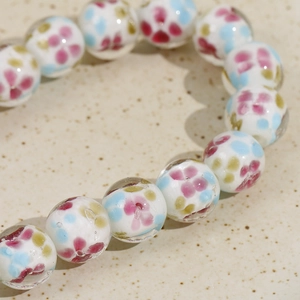 Close-up of 14mm round glass beads with colorful floral patterns for DIY jewelry making