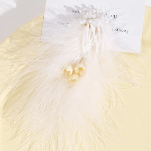 Détail d'une pince à cheveux en plumes d'autruche blanches avec perles et muguet