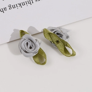 Detail of silver gray satin ribbon roses with green leaves for DIY clothing and crafts