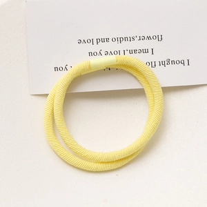 Detailed macro view of two lemon yellow elastic hair ties with fine ribbed texture