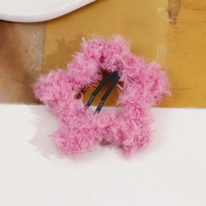 Close-up of pink plush star-shaped hair clip showing soft texture and metal fastener
