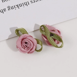 Macro detail of handmade pink satin rosebuds with green fabric leaves for DIY crafts