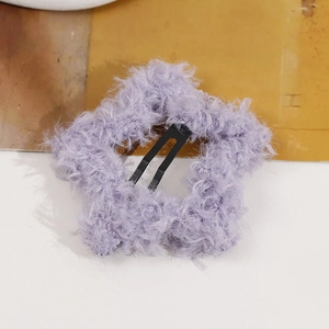 Detail view of a soft light purple plush star-shaped hair clip with metal BB grip texture