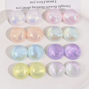 Close-up of glittery macaron-colored acrylic cabochons arranged in a white ceramic dish