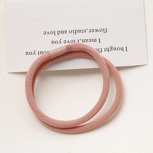 Close-up of two dusty pink elastic hair ties with textured fabric and seamless joints