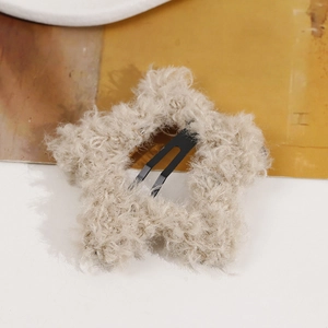 Close-up of a plush star-shaped hair clip featuring soft beige faux fur and metal BB clip