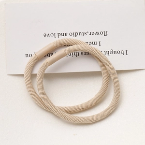 Close-up of beige elastic hair ties with woven texture on a minimalist card