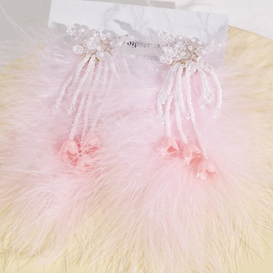 Détail de boucles d'oreilles en plumes d'autruche roses avec perles et fleur en résine