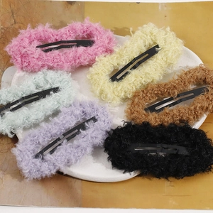 Detailed view of six colorful plush teddy fur rectangle BB hair clips on a white ceramic plate