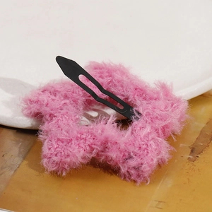Pink plush star hair clip with metal BB grip on a white ceramic plate background