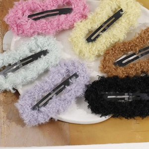 Close-up of colorful plush BB hair clips in six soft candy colors on a ceramic tray