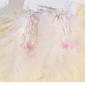 Détail de plumes d'autruche blanches et accessoires de cheveux perlés muguet rose poudré