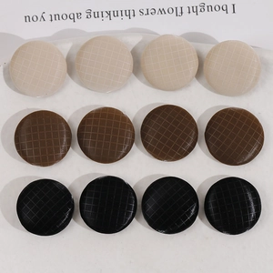 Close-up of 12 round plaid fabric buttons in beige, brown and black for DIY sewing