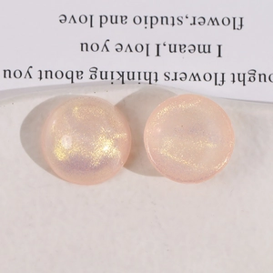 Macro detail of round pink resin buttons with golden purple glitter for DIY jewelry crafts