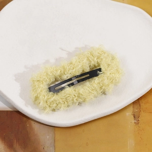 Close-up of yellow plush BB hair clip showing fuzzy texture and black metal snap part