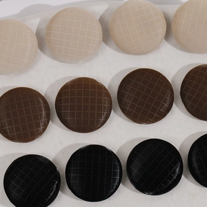 Detailed macro view of 17mm round fabric-textured buttons in beige, brown, and black colors