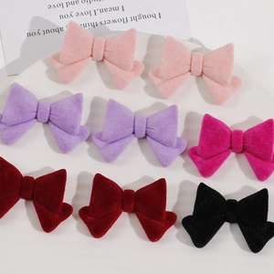 Multiple colorful flocked bow hair accessories in a round tray with a clean aesthetic