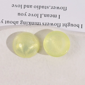 Detail of round yellow glitter acrylic charms with aurora finish on ceramic tray