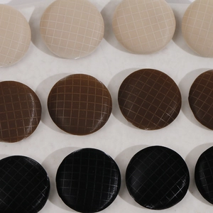 Close-up of 17mm round plaid fabric buttons in beige, brown and black for DIY sewing