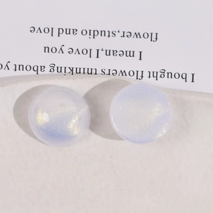 Close-up of sparkling round iridescent acrylic cabochons with purple and gold glitter