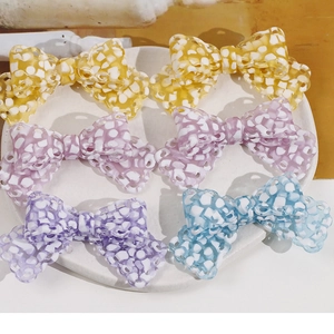 Close-up of assorted colorful acetate bow charms with unique mosaic texture on a tray