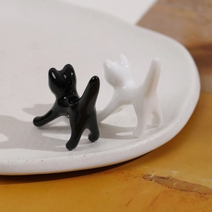 Figurine di gatto minimaliste in ceramica bianca e nera in posa di allungamento