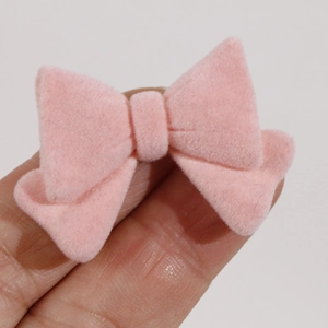 Pink velvet flocking bow accessory for DIY jewelry making held in hand for scale