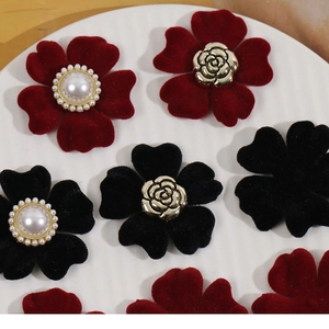 Dettaglio di ciondoli a fiore floccato rossi e neri con perle e rose dorate