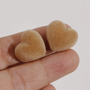 Vue détaillée de boucles d'oreilles floquées en forme de cœur kaki entre les doigts