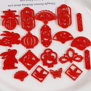 Flat lay of red acrylic Chinese New Year charms including lanterns, rabbits, and fan shapes